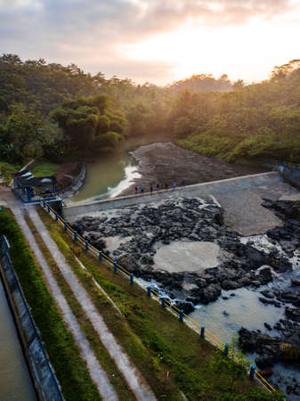 Dried dam with a small flow of water. It is surrounded by trees and looks like a rocky stream. Central Java, Indonesiaの写真素材