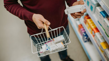 Man buying medicines in the drugstore. Close-up of male hands holding shopping cart with medicines.の素材
