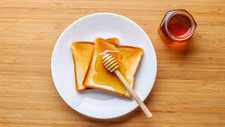 Toasted bread with honey and honey dipper on a wooden backgroundの素材