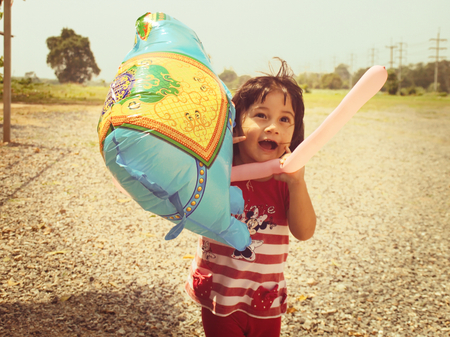 Vintage style picture of a 2-year-old Asian-Caucasian girl playing with a balloonの写真素材