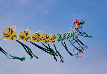 a string of colorful chinese kites depicting chinese traditional masks are floating before blue skyの写真素材