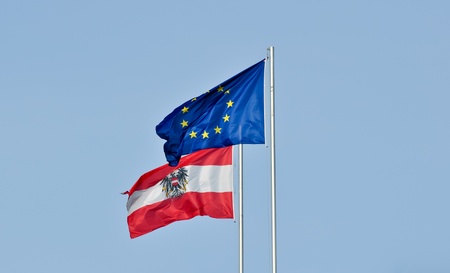 flags of austria and the european union flying together against a blue sky