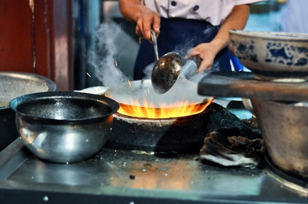 asian cook cooking with a wok on a gas flameのeditorial素材