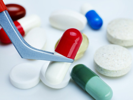 Holding a pill with tweezersの写真素材