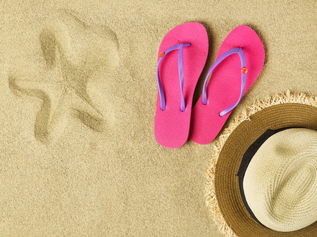 Slippers and hat on sandの写真素材