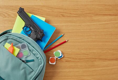 Backpack, school supplies and gun on desk