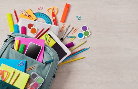 Backpack full with school supplies on a wooden table