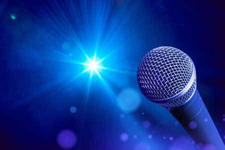 Vocal microphone in front of blue-toned stage lightsの写真素材