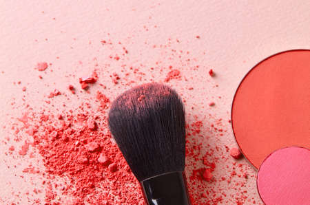 Eyeshadow and brush close-up on pink background