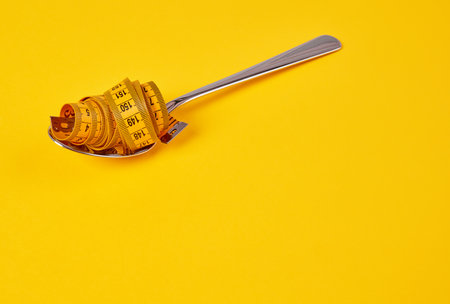 Tape measure in a spoon, diet conceptの写真素材