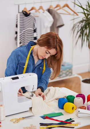 Female fashion designer working on sewing machine