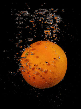 Orange splashing in water on a black backgroundの写真素材