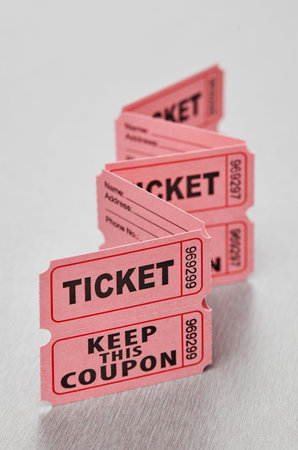 Pink raffle tickets folded in zigzag row on light background