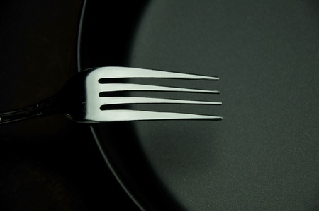 fork in black plate as white isolate background