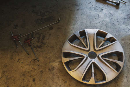 A hubcap and tools on the floor in a car serviceの写真素材