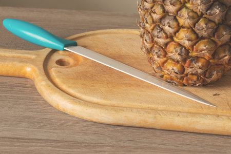 Close-Up of Pineapple and Knife on a wooden chopping boardの写真素材