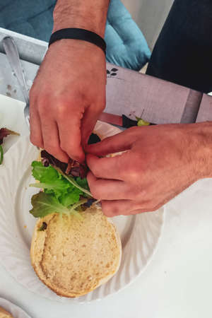 Close-up of male hands preparing a vegetarian burger in the kitchen. Top view, copy spaceの写真素材
