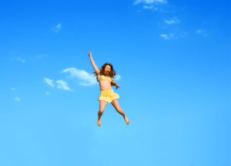 The happy jumping girl on a background of the blue skyの写真素材