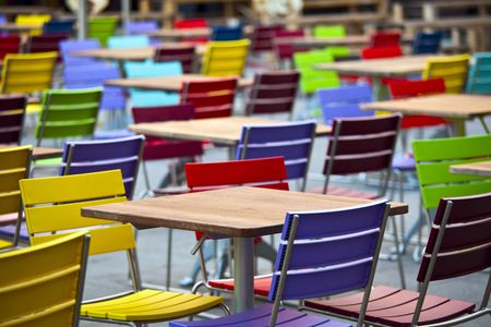 Empty dining tables and coloured chairs in a street cafeの写真素材