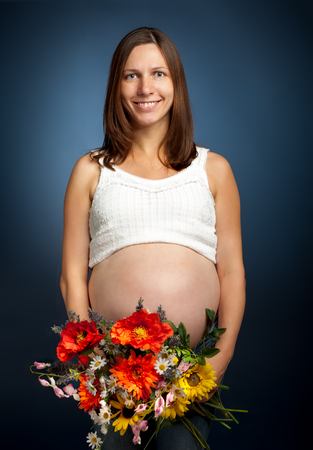 Beautiful pregnant woman with a bouquet of flowers.の写真素材