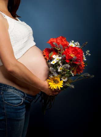 Beautiful pregnant woman with a bouquet of flowers.の写真素材