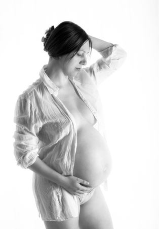 pregnant woman, expectant mother on white background, close-up of pregnant belly, monoshrome shoot.の写真素材