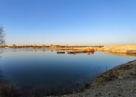 excavation machine at earthmoving work in sand quarry. Extraction of sand from a lake.