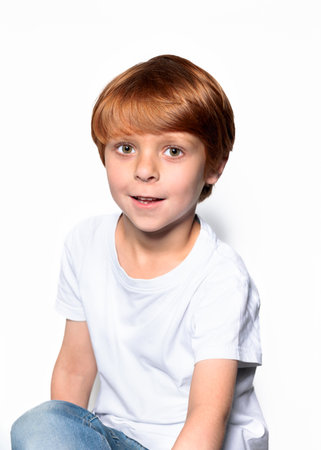 Red-haired boy in white t-shirt close-up cropped view at gray backgroundの写真素材