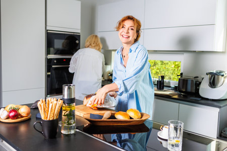 Two Women Preparing Fresh Bread and Coffee in a Bright Kitchenの写真素材
