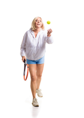 A determined and athletic woman is engaged in playing tennis, wearing sporty clothing and holding a tennis racket. She is focused on her game, showcasing agility and strength. The white background emphasizes her movements, highlighting her passion for the sport and active lifestyle.の写真素材