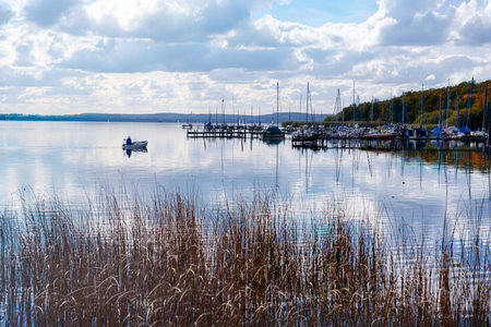 Images of Steinhuder Meer Lake showcasing its serene waters, lush greenery, and cloudy skies. The photos capture the natural beauty and tranquility of the lake, highlighting its calmness and vibrant reflections of the surrounding landscape.の写真素材