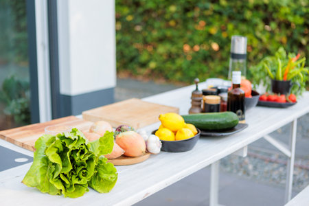 Outdoor setup with fresh ingredients on a table, including tomatoes, green peppers, and spices. A cozy patio setting with a natural, rustic atmosphere.の写真素材