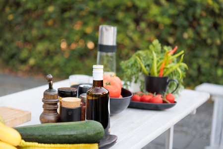 Outdoor setup with fresh ingredients on a table, including tomatoes, green peppers, and spices. A cozy patio setting with a natural, rustic atmosphere.の写真素材