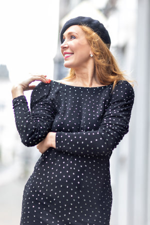 Stylish woman wearing a short polka dot dress and glittering cowboy boots walking and posing on a cobbled street in a historic European townの写真素材