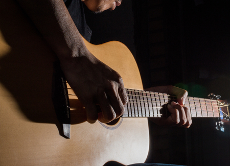 playing acoustic guitar on low-key lighting backgroundの写真素材