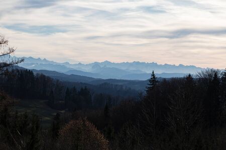elongated mountain range covered with blue haze at sunset at dusk in autumn