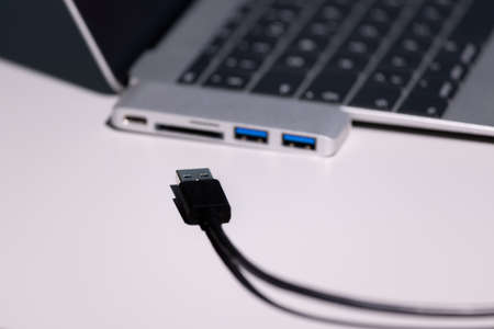 supermacro photo shot focused on a black usb a cable, usb to usb-c adapter and laptop are strongly...