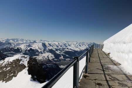 Santis Terrace, walkway with steel railing, view of the seven churfirsten under a cloudless blue...