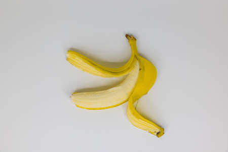 single peeled yellow banana on white background, studio shot, fruits are healthyの写真素材