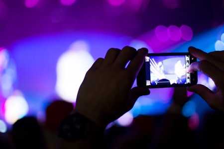 Close up of photographing with smartphone during a concert
