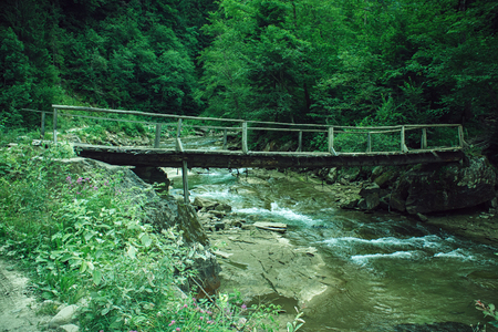 Old wooden bridge on mountain riverの写真素材
