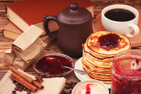 Table with pancakes and black currant jam, books and coffeeの写真素材