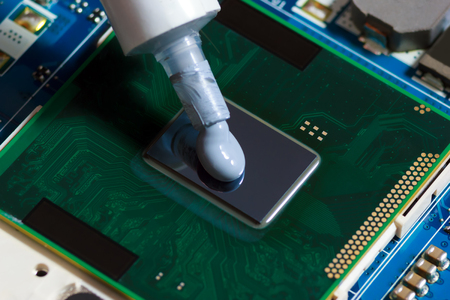 Thermal paste compound squeezing on processor of notebook. Thermal grease for better cooling of deviceの写真素材
