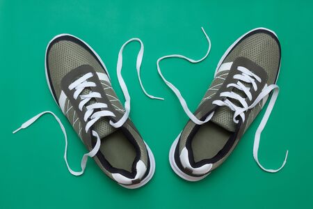 Olive color sport shoes sneakers pair with white shoelaces on solid green background, top viewの写真素材