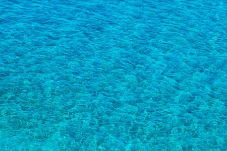 Vibrant blue color surface of sea. Top view on clean sky blue sea water with small waves. Summer sea water texture backgroundの写真素材