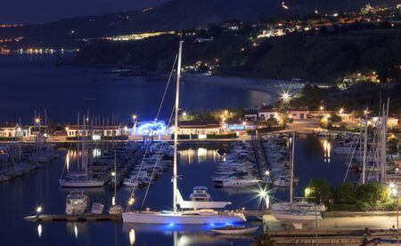 Tropea, Italy - September 6, 2019: Panorama of Tropea yacht sea port with beautiful night colorful lights. Night illumination of Tropea city, Calabriaのeditorial素材