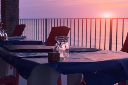 Evening terrace of cafeteria near the sea coastline. Sunset with dusk lighting.
