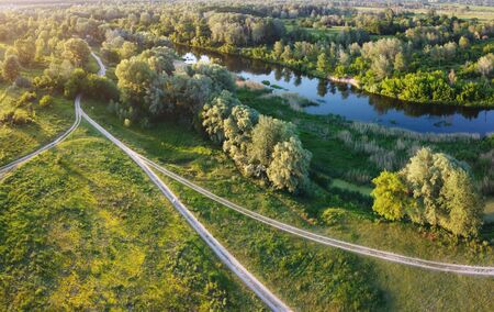 Rural riverside at evening with ground pathway and roadの写真素材