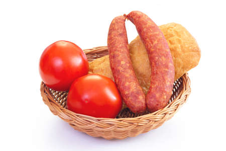 Wicker bowl with ciabatta bread, smoked sausage and tomatoes. Village food composition.の写真素材