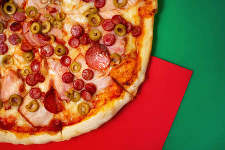 Pepperoni pizza with ham and  smoked sausages on red and green background with copy space areaの写真素材